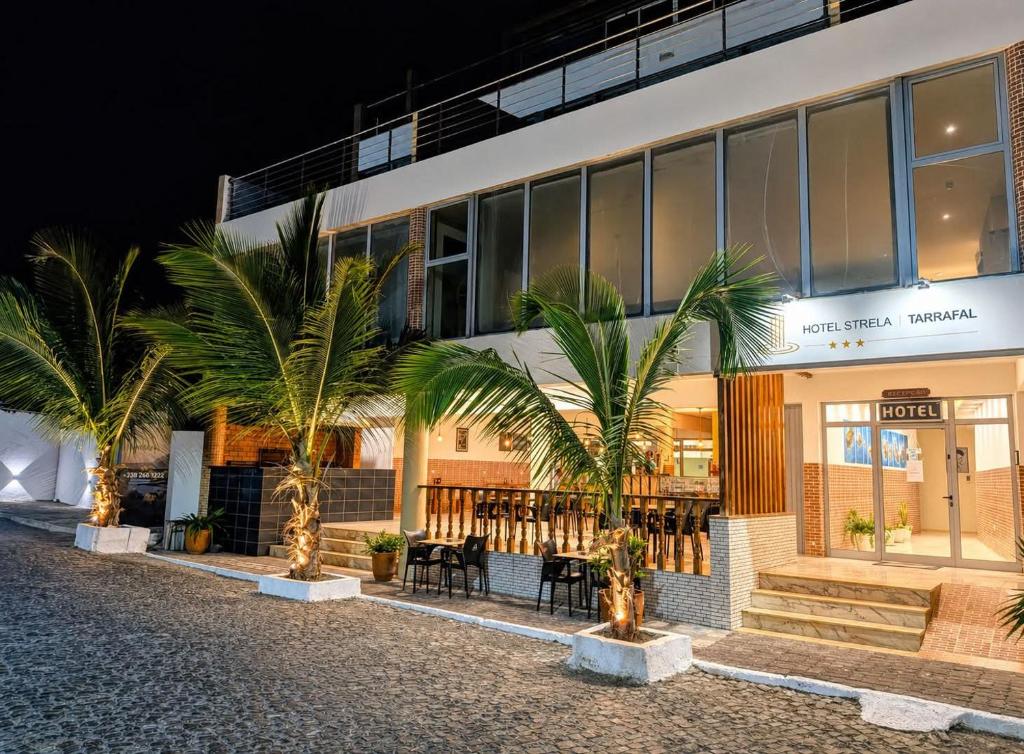 a building with palm trees in front of it at Hotel Strela Tarrafal in Tarrafal