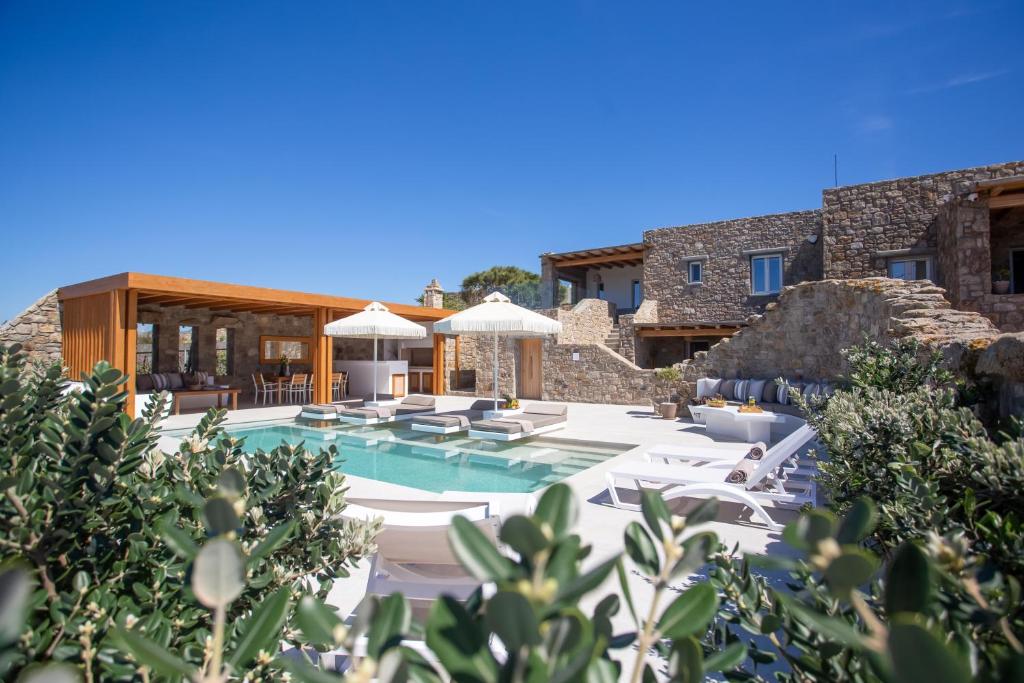 a pool with white chairs and umbrellas at Mystic Harmony in Mikonos