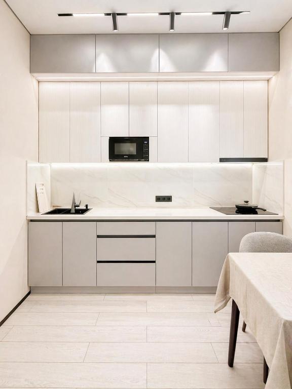 a kitchen with white cabinets and a microwave at River City Residence in Almaty