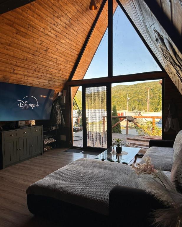 a living room with a couch and a large window at Cabin&Villa Property in Târgu Ocna