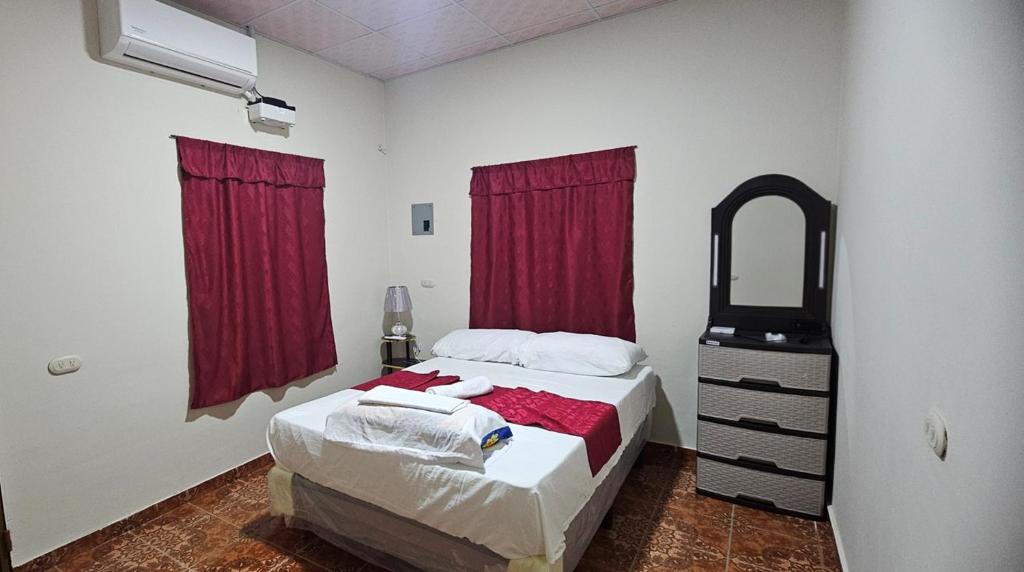 a bedroom with a bed and a mirror and red curtains at María House in San Miguel