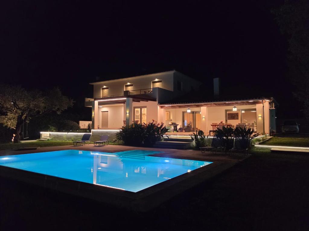 a house at night with a swimming pool in front of it at V Mira Luxury Villa in Tragaki