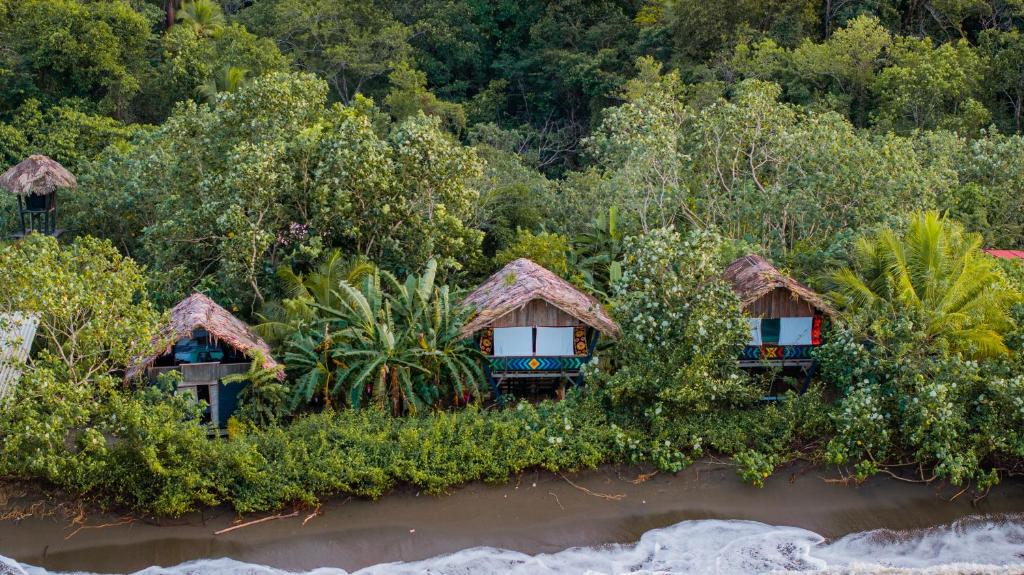 a group of huts on the side of a river at El Vijo Surf in Nuquí