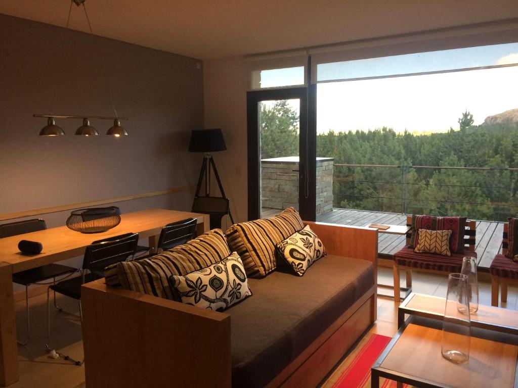 sala de estar con sofá y ventana grande en Golf y Polo Apartment en San Martín de los Andes