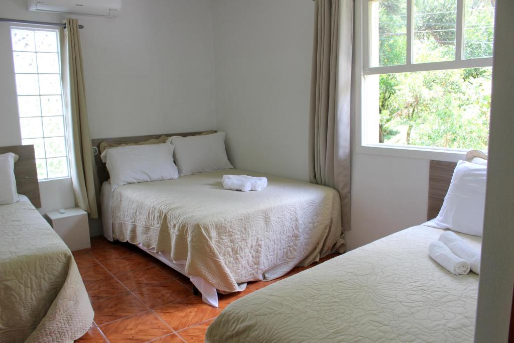 a bedroom with two beds and a window at Kantinho da Serra in Nova Petrópolis