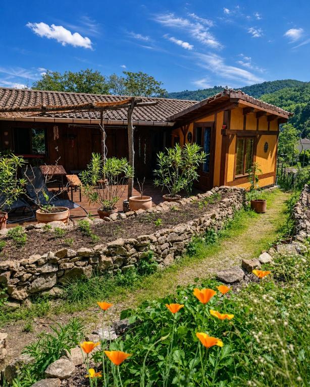 a house with a stone wall and flowers in front at Cocon-ardechesauvage in Pont-de-Labeaume