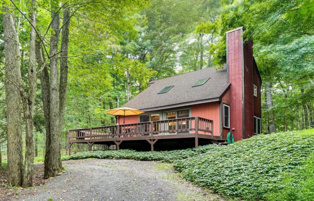 a red house with a deck in the woods at Pine Loch, sleeps 9, 3 bedroom, 2 bath, gas fire pit on deck in Pocono Lake