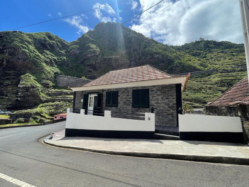 a small house on the side of a road with a mountain at Rdj B in Porto Moniz