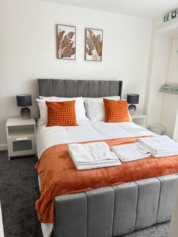 a bedroom with a large bed with orange pillows at Seaside Apartments Redcar in Redcar
