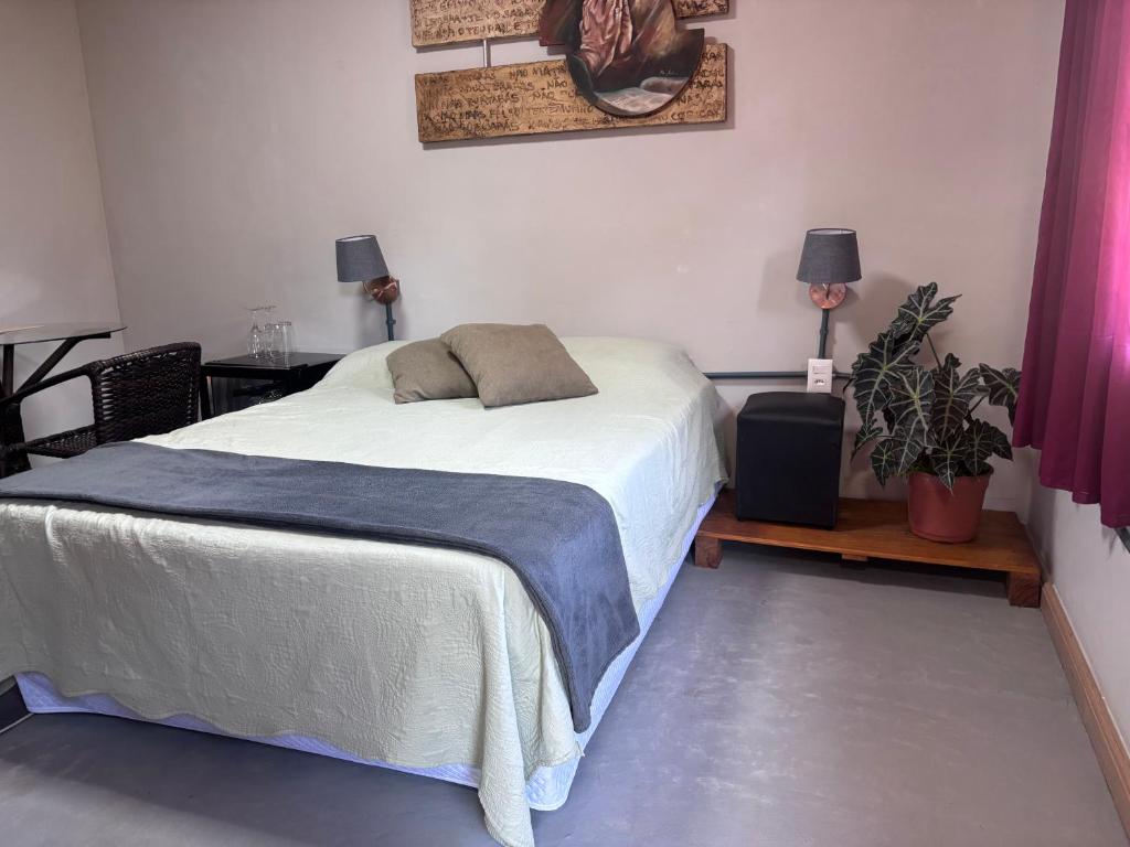 a bedroom with a bed and two lamps and plants at Recanto dos Querubins in Cambé
