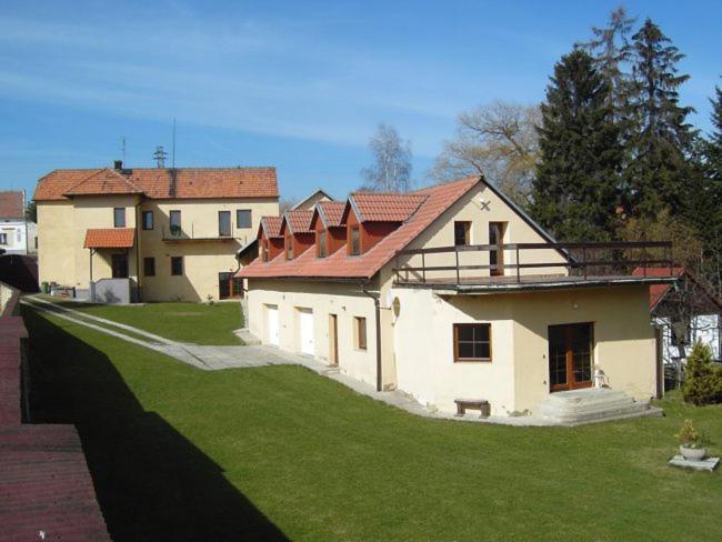 a house with a green yard next to a building at Apartmán Andels I in Rakovník