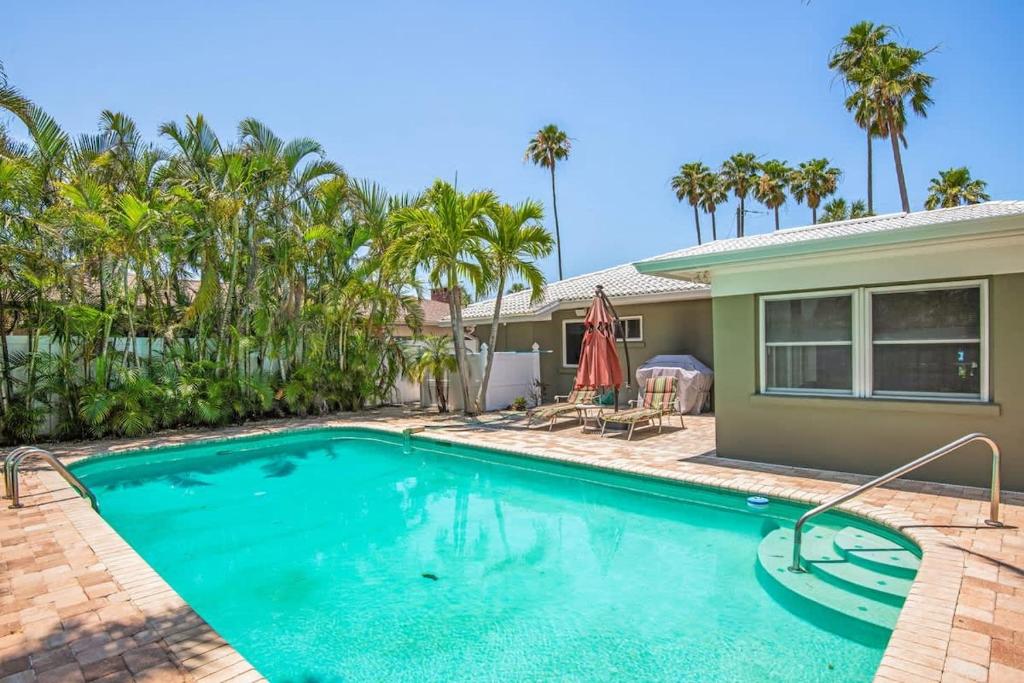 a swimming pool in front of a house with palm trees at Clearwater Calling in Clearwater Beach