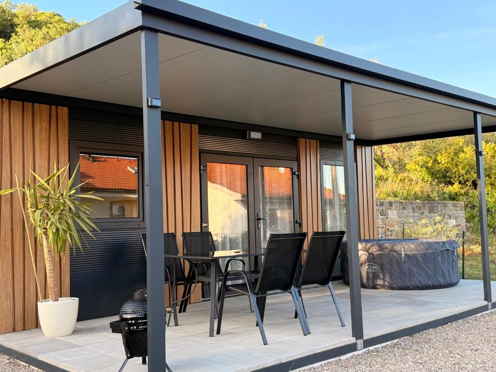 a pavilion with chairs and a table on a patio at Mobile House Aurora with whirlpool in Ankaran