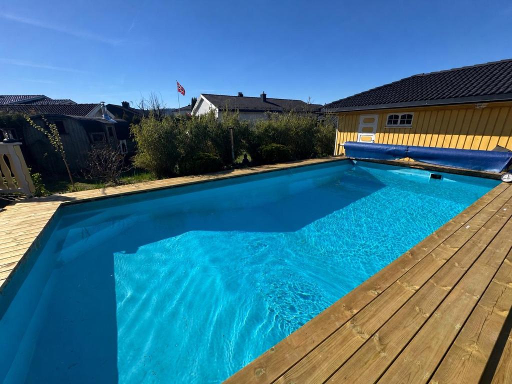 a large blue swimming pool with a wooden deck at Pool & Sauna Retreat - Private Studio Apartment Porsgrunn in Porsgrunn