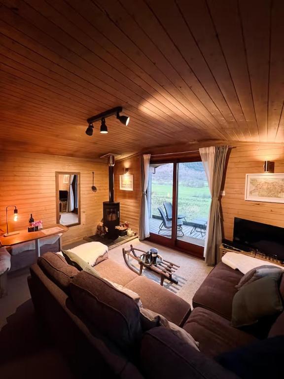 a living room with a couch and a large window at Cosy Log Cabin in Machynlleth - Wales - Wifi & Parking in Machynlleth
