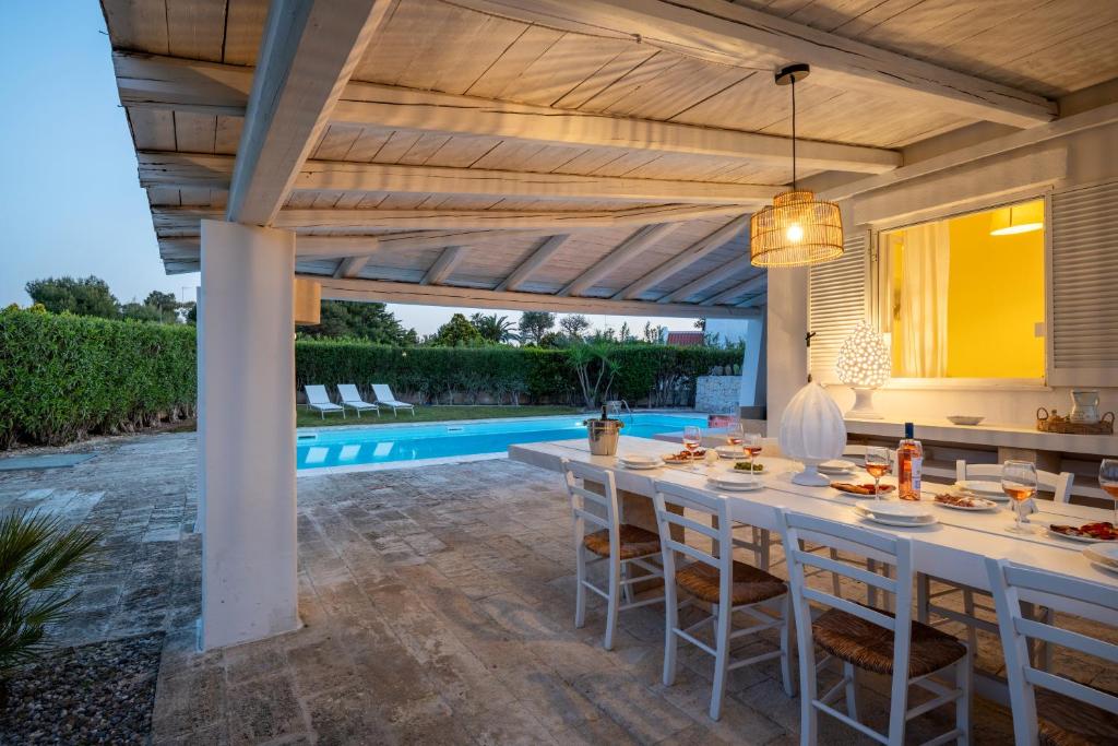 a patio with a table and chairs and a swimming pool at Serena Armando Exclusive Villas with Private Pools in Rosa Marina