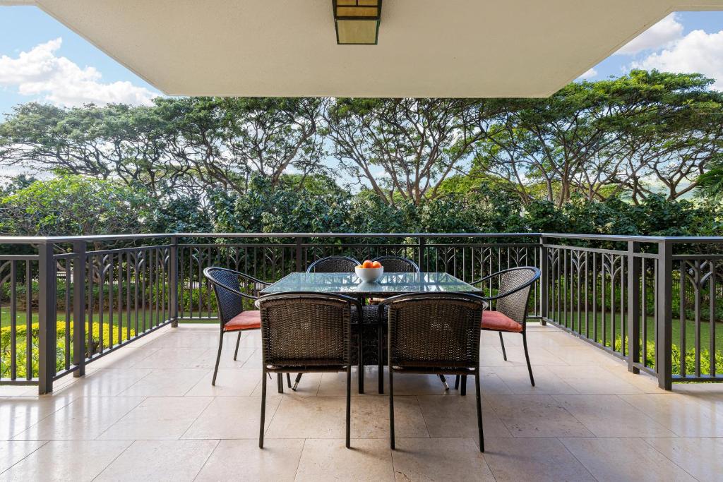 a table and chairs on a balcony with trees at Ko Olina Beach Villas B204 in Kapolei