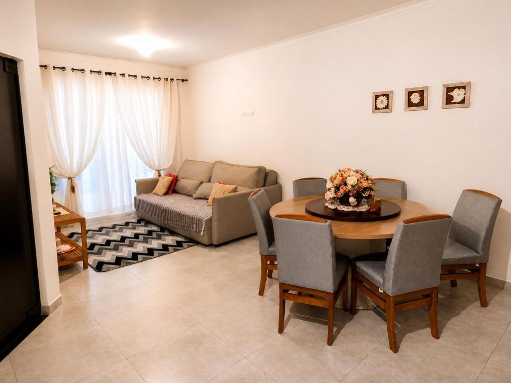a living room with a table and a couch at Casa da Cle, 2 quartos com ar condicionado, 600m da praia in Itapoa