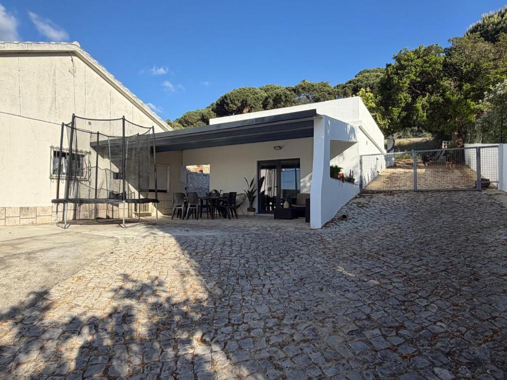 a white house with a stone driveway at Alex Guest House in Quinta do Anjo