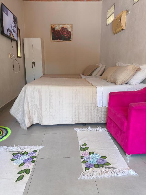 a bedroom with a large bed and a pink couch at Hospedagem casa da Lu in Paraty