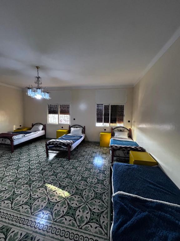 a room with three beds in a room with a carpet at Tabriquet urban shared room in Salé