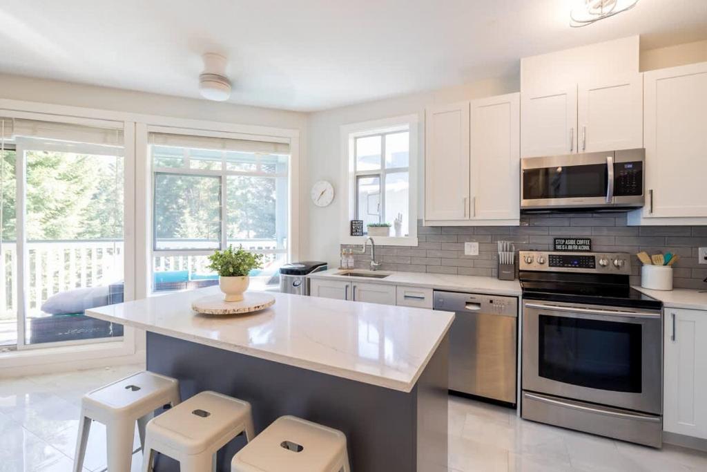 a kitchen with white cabinets and a kitchen island with stools at Panoramic Views from this gorgeous 2 Bed Property - Village Location in Whistler