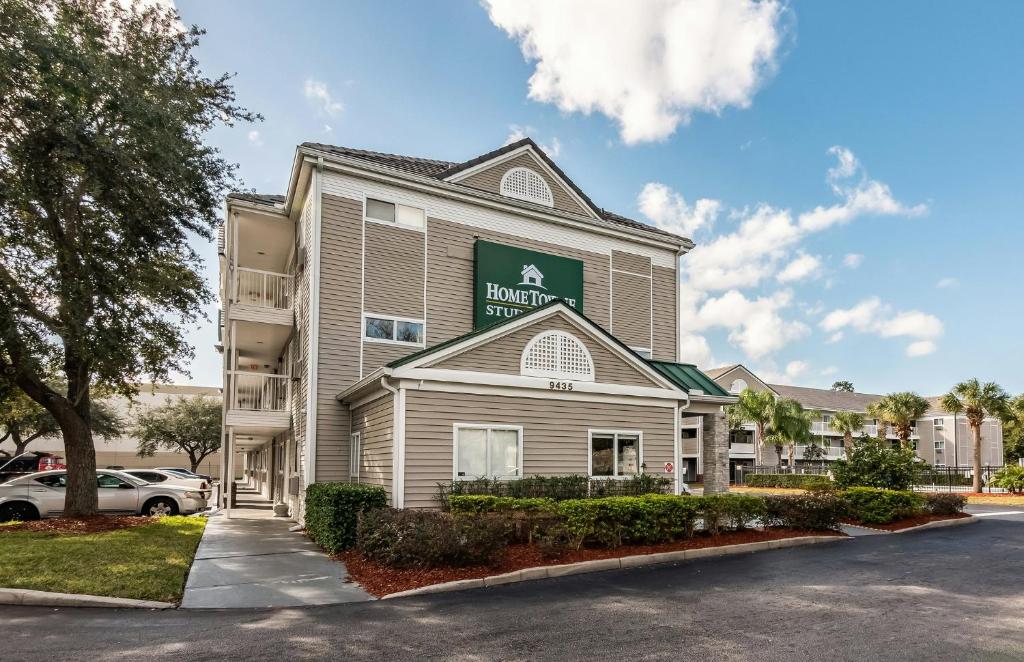 a front view of a hotel with a parking lot at HomeTowne Studios by Red Roof Orlando South in Orlando