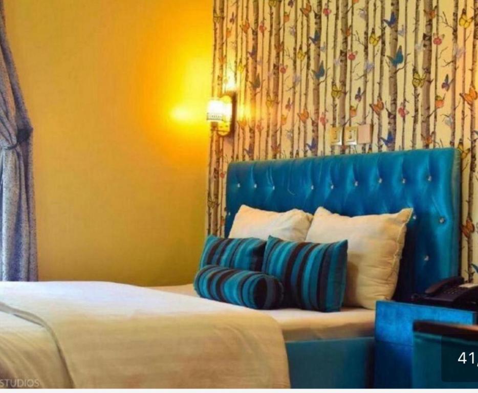a bedroom with a bed with a blue headboard and pillows at Benyster Hotel in Gwarinpa