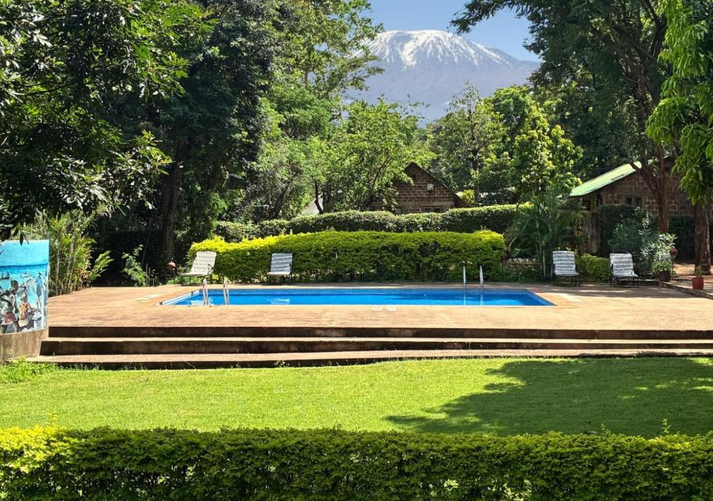 a swimming pool with a mountain in the background at Kilimanjaro Lodge - MCF in Moshi