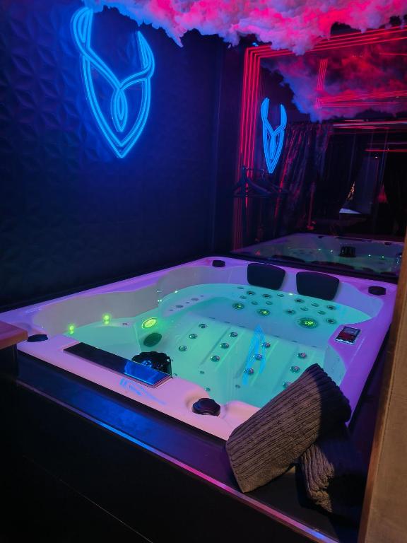a jacuzzi tub in a room with a neon sign at Luxuria - Jacuzzi et Hammam in Le Cannet