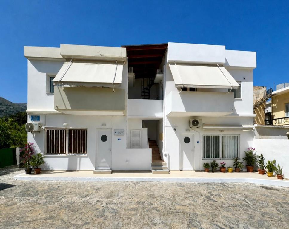 a white house with two awnings on it at Elounda Square Home in Elounda