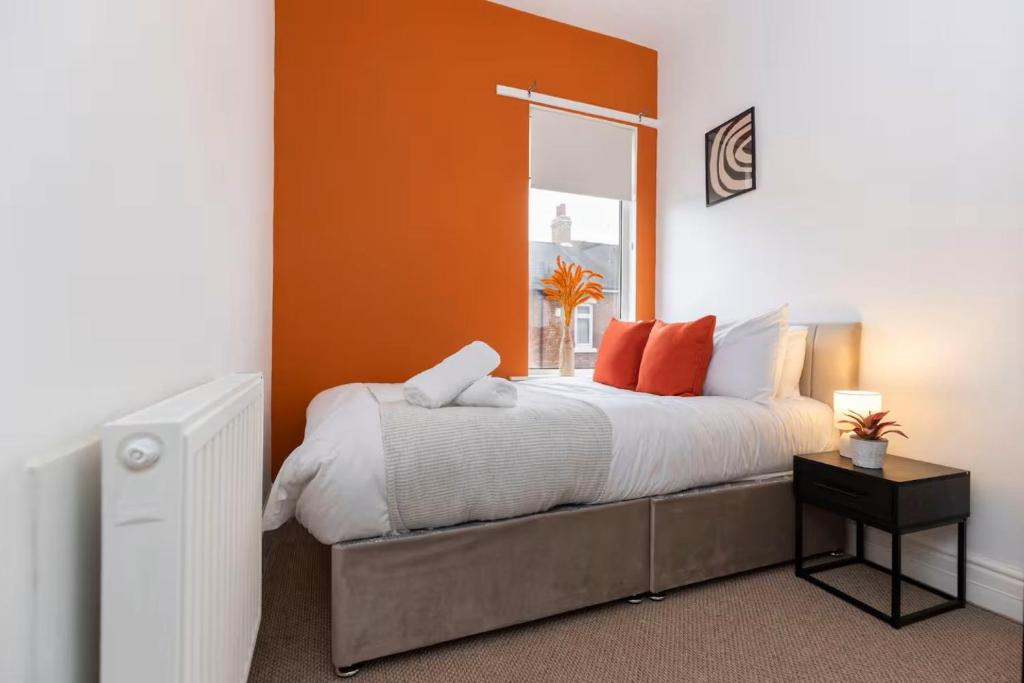 a bedroom with a bed with an orange wall at 3BR Home in Darlington Contractor Rates in Darlington