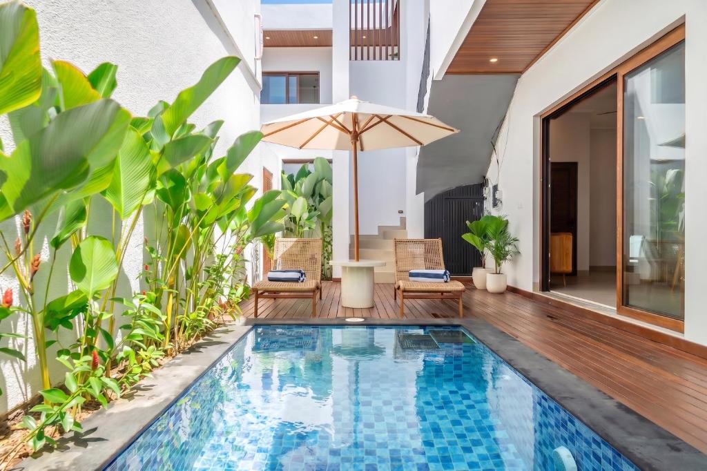 an indoor pool with chairs and an umbrella next to a house at Cassandra Villas - Tropical Private Pool Escape near Beach in Sanur