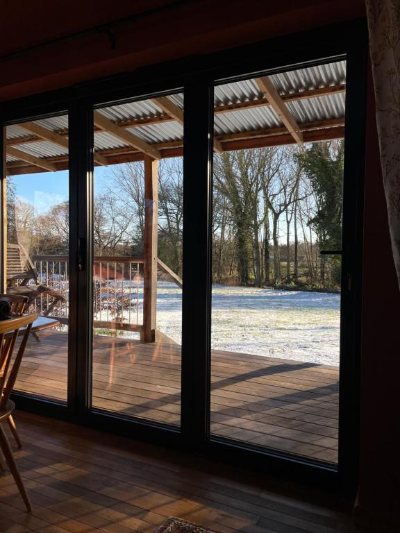 a sliding glass door with a view of a deck at Zambezi Cabin in Halesworth