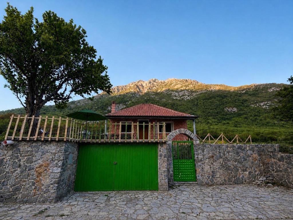 a building with a green garage with a fence at Villa Adi in Ducaj