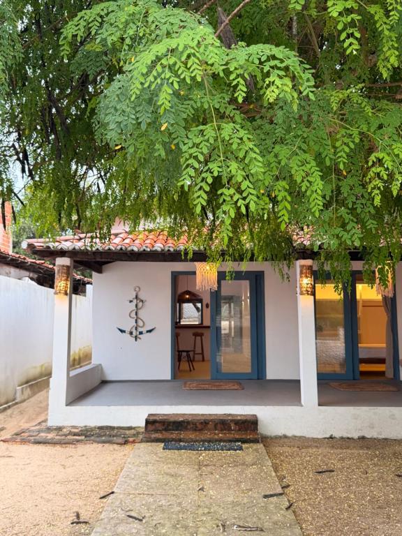 a small white house with a tree at Casa Pema - Grupo Casa Camurupim in Barra Grande