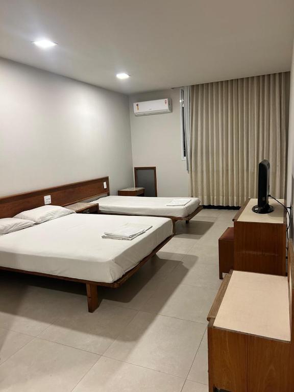 a room with three beds and a television in it at Hotel Mata da Praia in Vitória