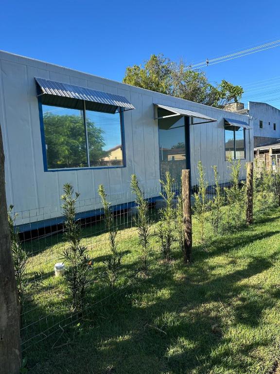 a house with a fence and trees in the yard at Casa Container Completa e Privativa em Sombrio-SC in Sombrio