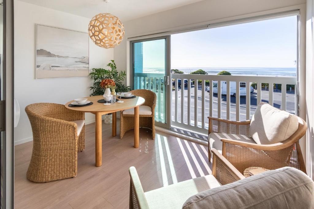 a living room with a table and chairs and a balcony at Waves & Wellness - Spa Pool and Parking in Christchurch