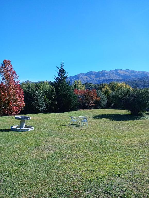 two benches in a grassy field with mountains in the background at Loft Las Acacias in Potrero de los Funes