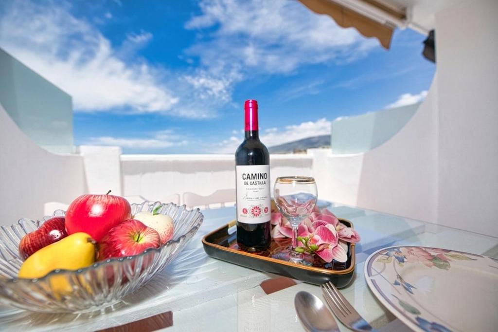 a bottle of wine and a bowl of fruit on a table at Ocean Paradise View in Adeje