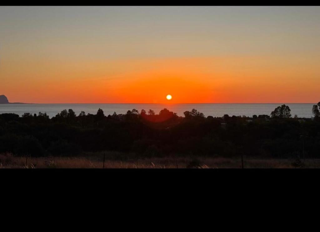 a sunset over the ocean with the sun in the sky at Oikos Terrasini in Terrasini