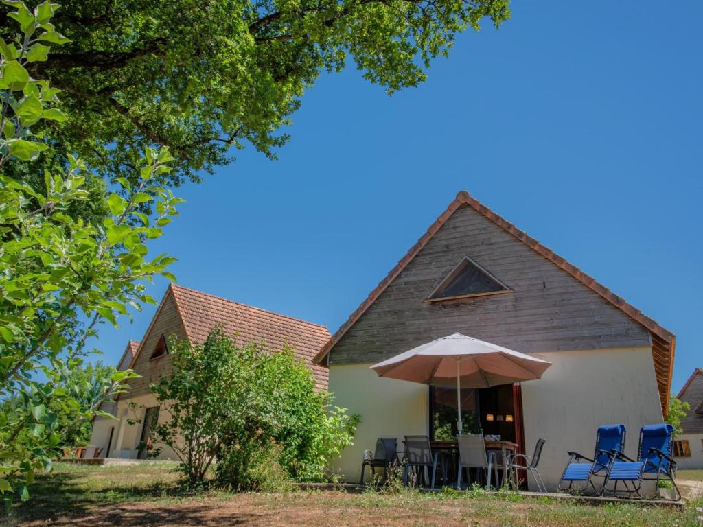 a house with chairs and an umbrella at Lac Bleu huis nr 13 in Lacapelle-Marival