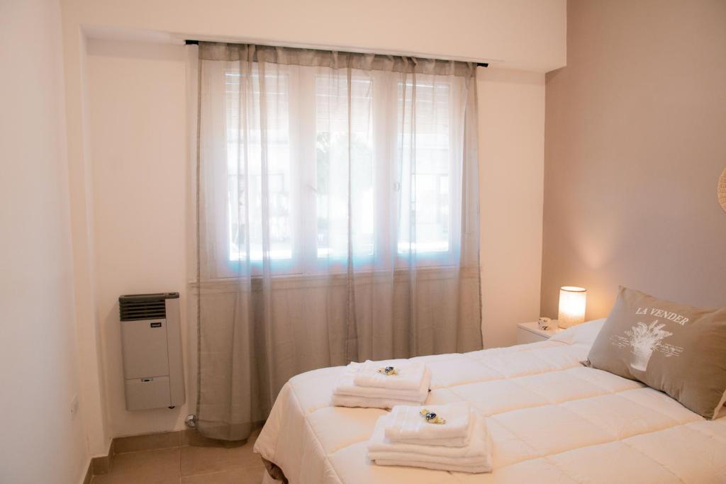a bedroom with a white bed with towels on it at Epoca in Tandil