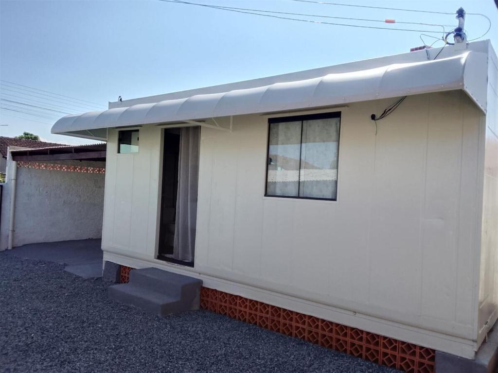 a white house with a window and a door at Container Loft Com Área de Churrasqueira Privativa in Piçarras