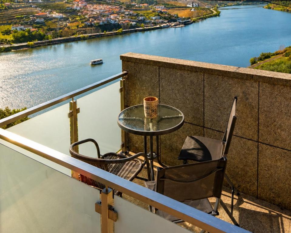 a table and chairs on a balcony with a view of a river at Vivenda Portela in Covelinhas