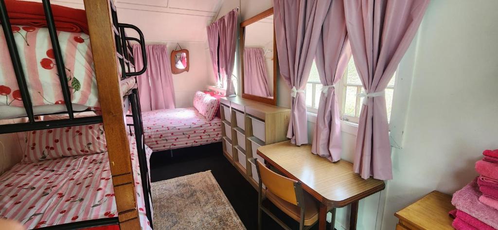 a small room with bunk beds with pink curtains at Meyenburg Family Room in Mount Morgan