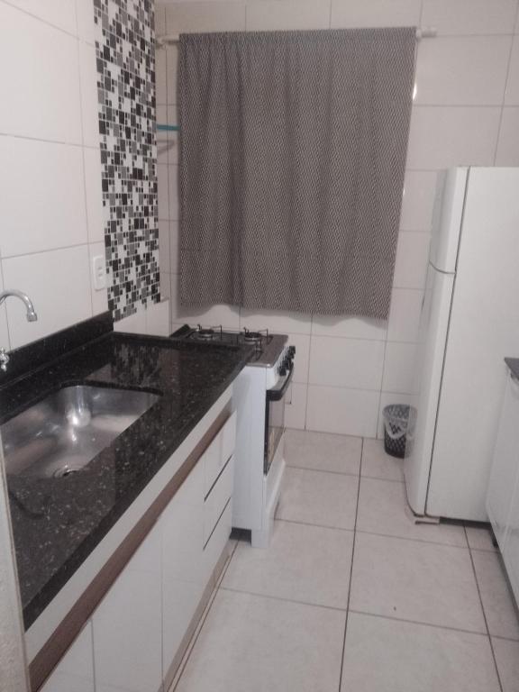 a kitchen with a sink and a black counter top at Ap Simples arc, bem localizado confortável e aconchegante, 2 quartos in Araçatuba