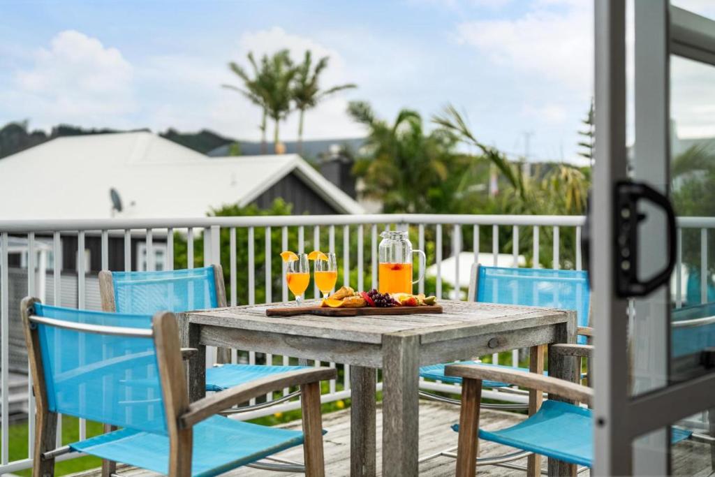a wooden table with blue chairs and drinks on a deck at Ocean Road Beach House in Whangamata