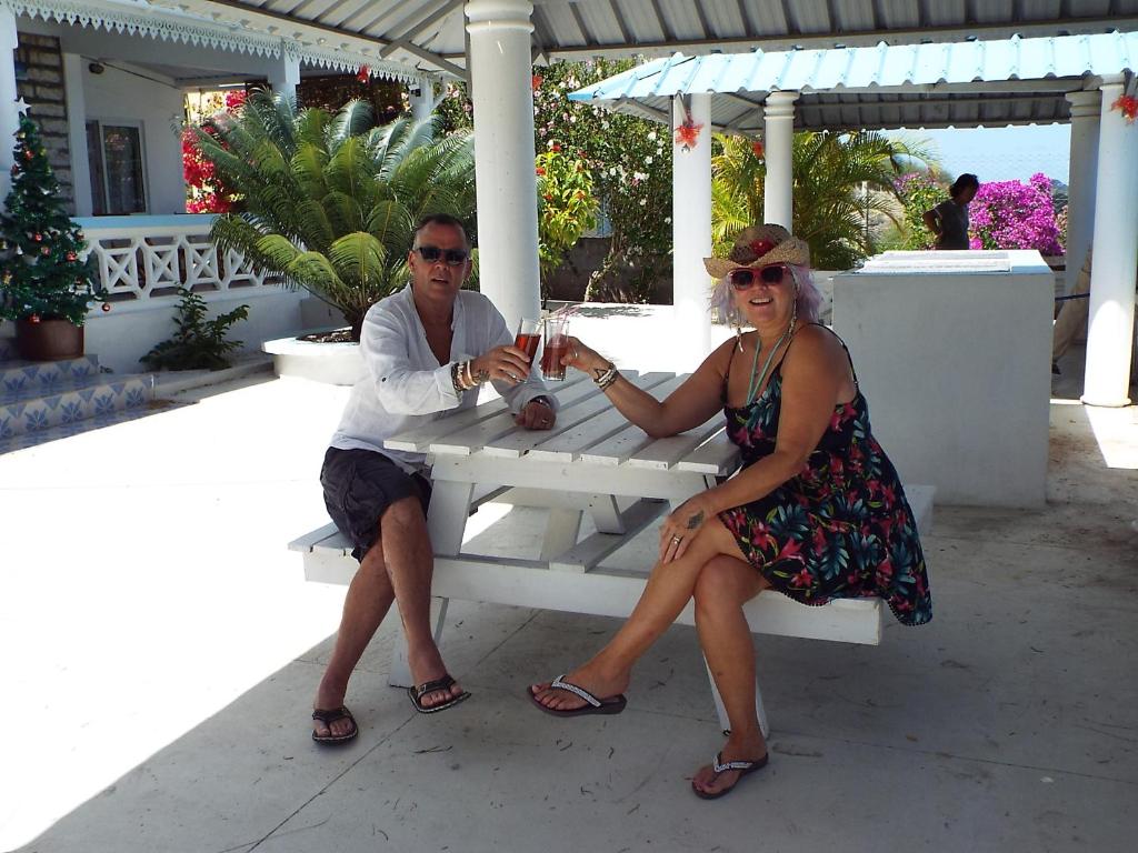 un hombre y una mujer sentados en un banco blanco en Le Paradiso Apartments, en Rodrigues Island